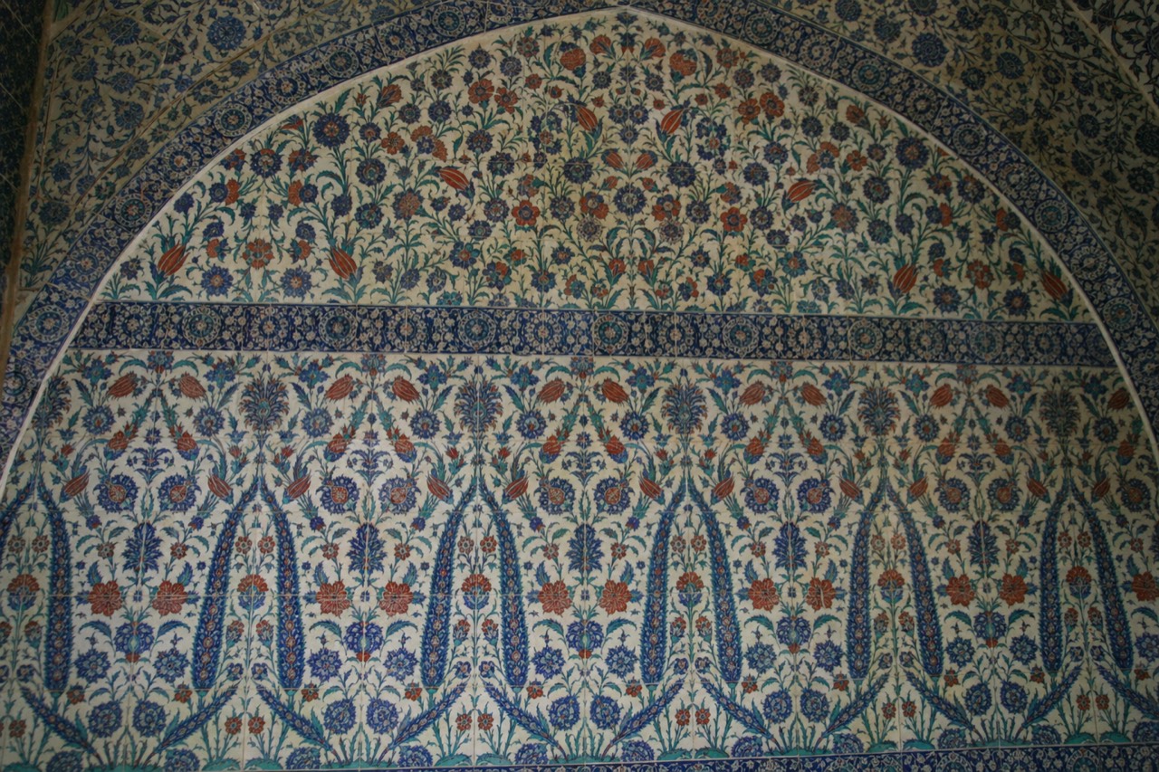 A full wall of blue, turquoise and coral-red Iznik floral tiles beneath a pointed arch at Topkapi Palace in soft natural light