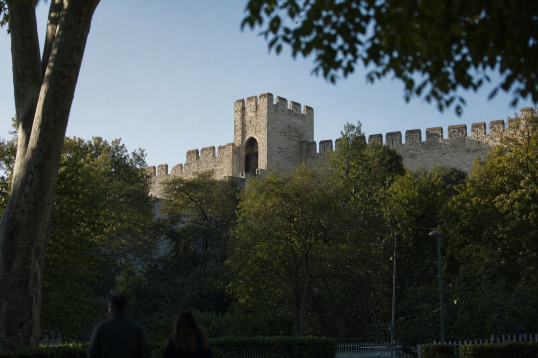 Crenellated outer walls and a stone gate of Topkapi Palace above the trees of Gulhane Park