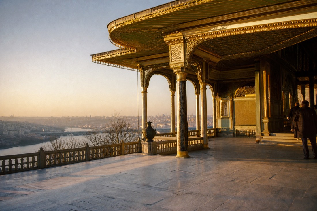 Gilded canopied pavilion on a Topkapi Palace terrace overlooking the Golden Horn at golden hour