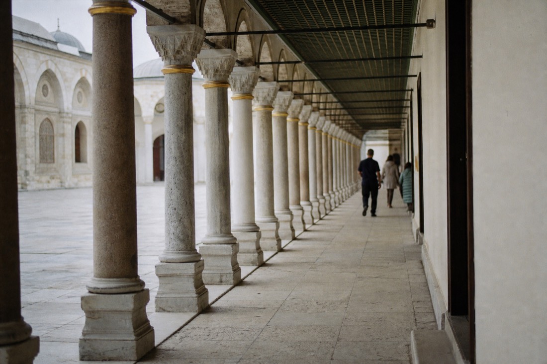 Long colonnade walkway with marble columns in a Topkapi Palace courtyard at midday