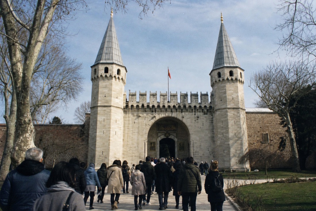 The Gate of Salutation at Topkapı Palace with its two pointed towers, visitors approaching the entry